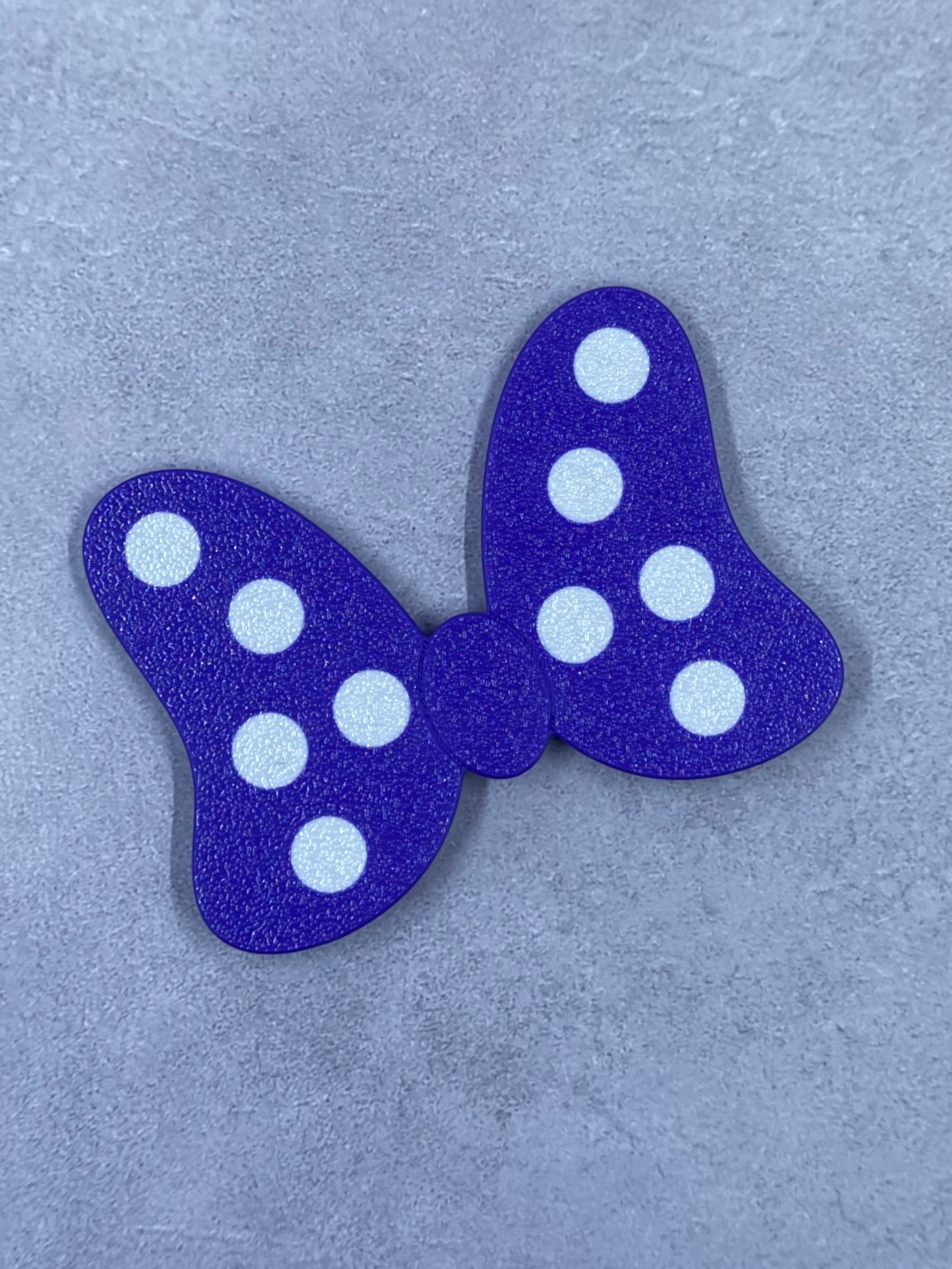 A purple glitter bow with white polka dots.